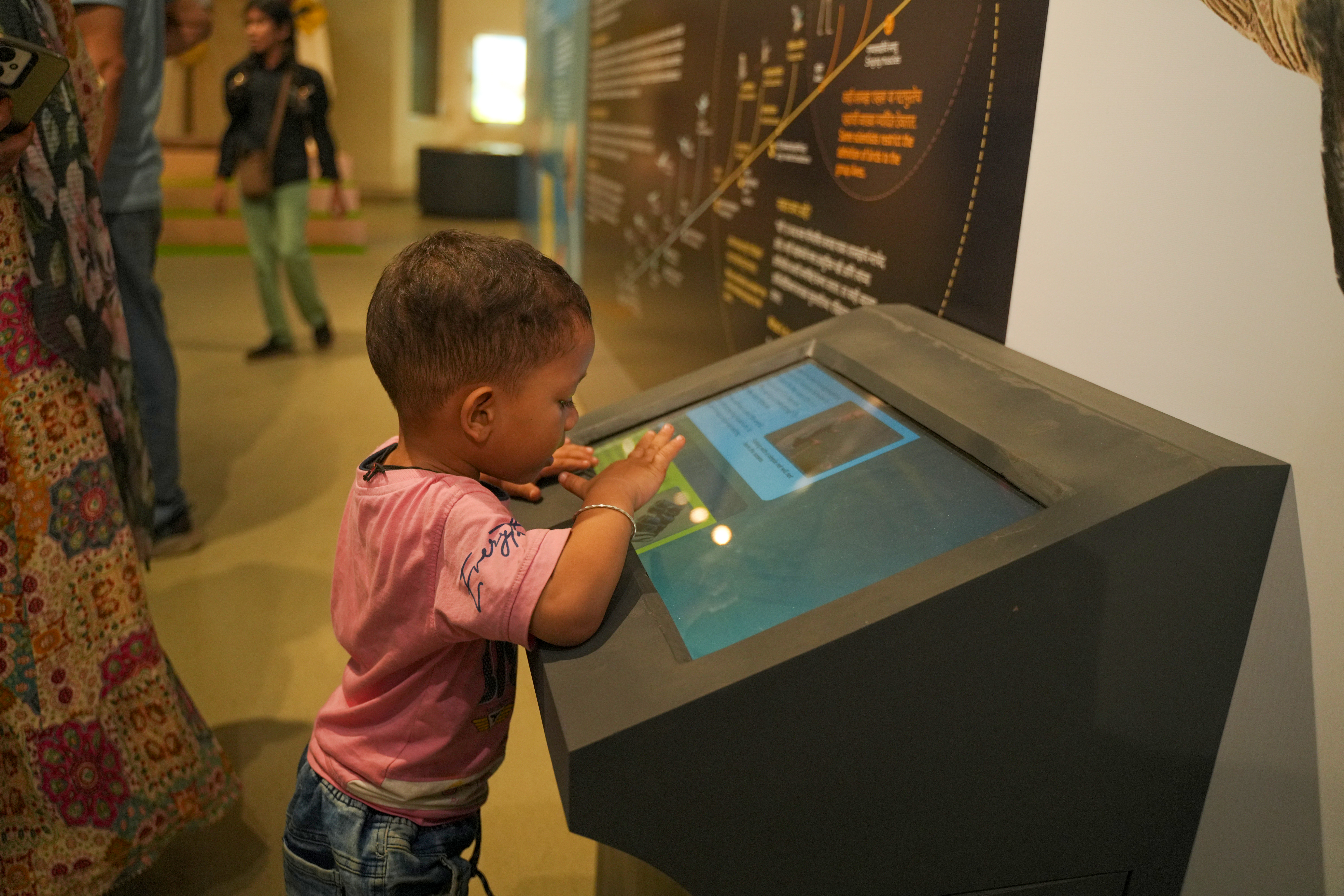 A toddler using a touchscreen kiosk on the exhibition floor