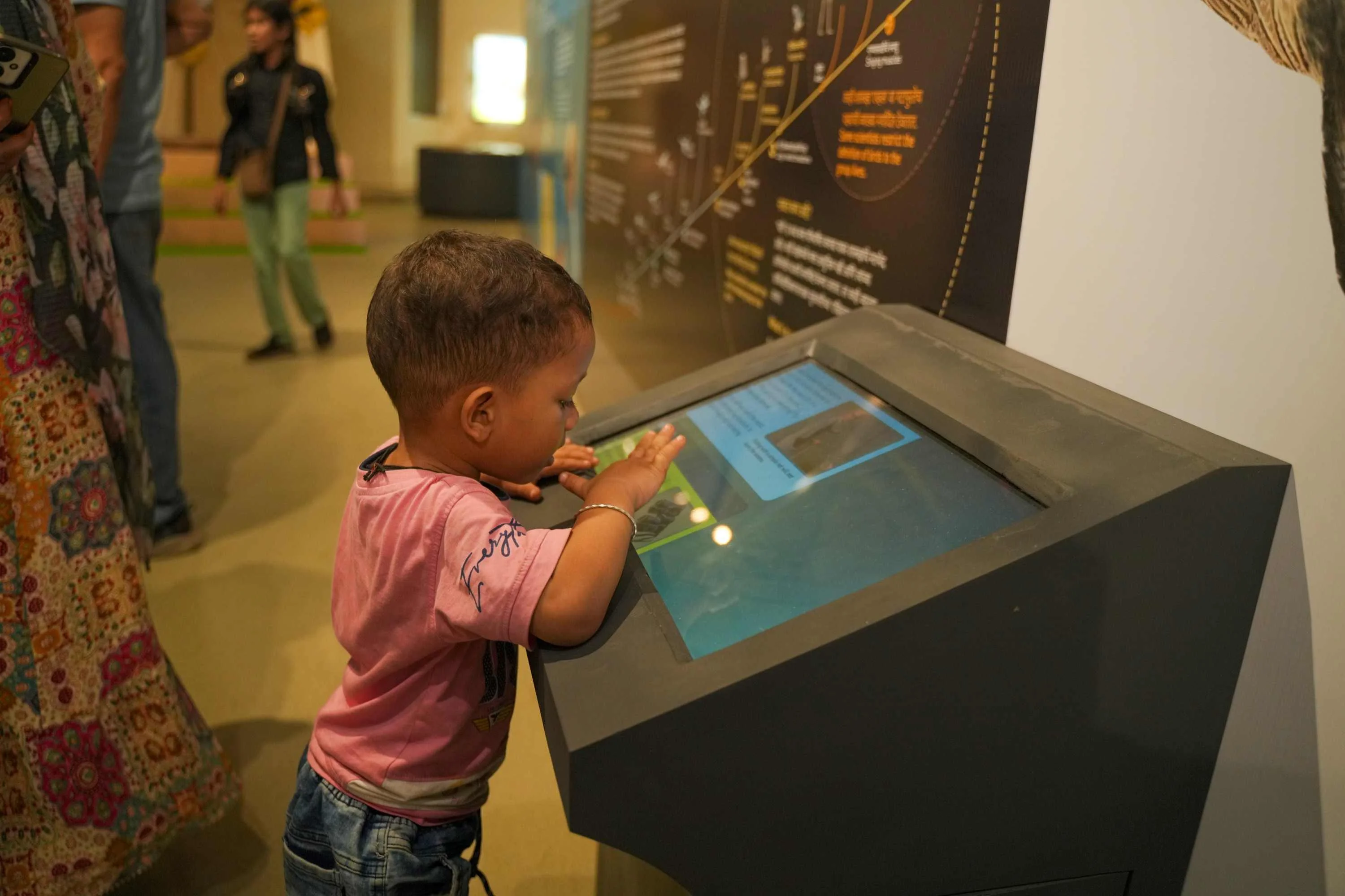 A toddler using a touchscreen kiosk on the exhibition floor