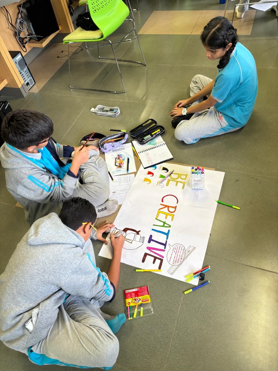 Students building a poster together on the floor during a bootcamp