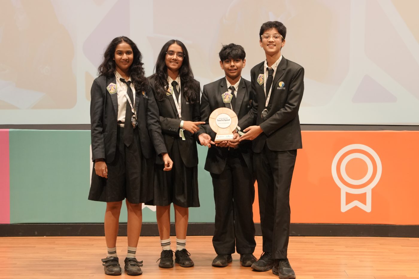 Four students on stage holding the Young Pioneers Launchpad trophy