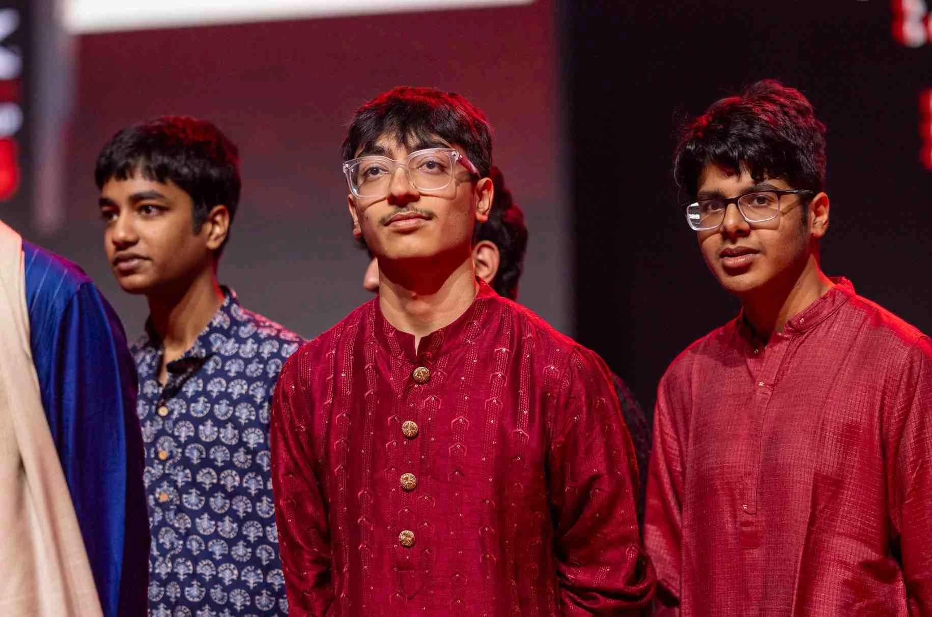Three Indian students on stage in kurtas during the ceremony