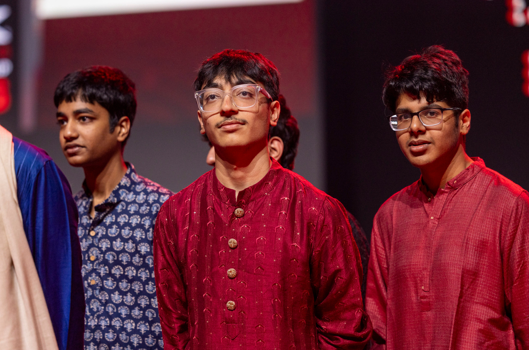 Three Indian students on stage in kurtas during the ceremony