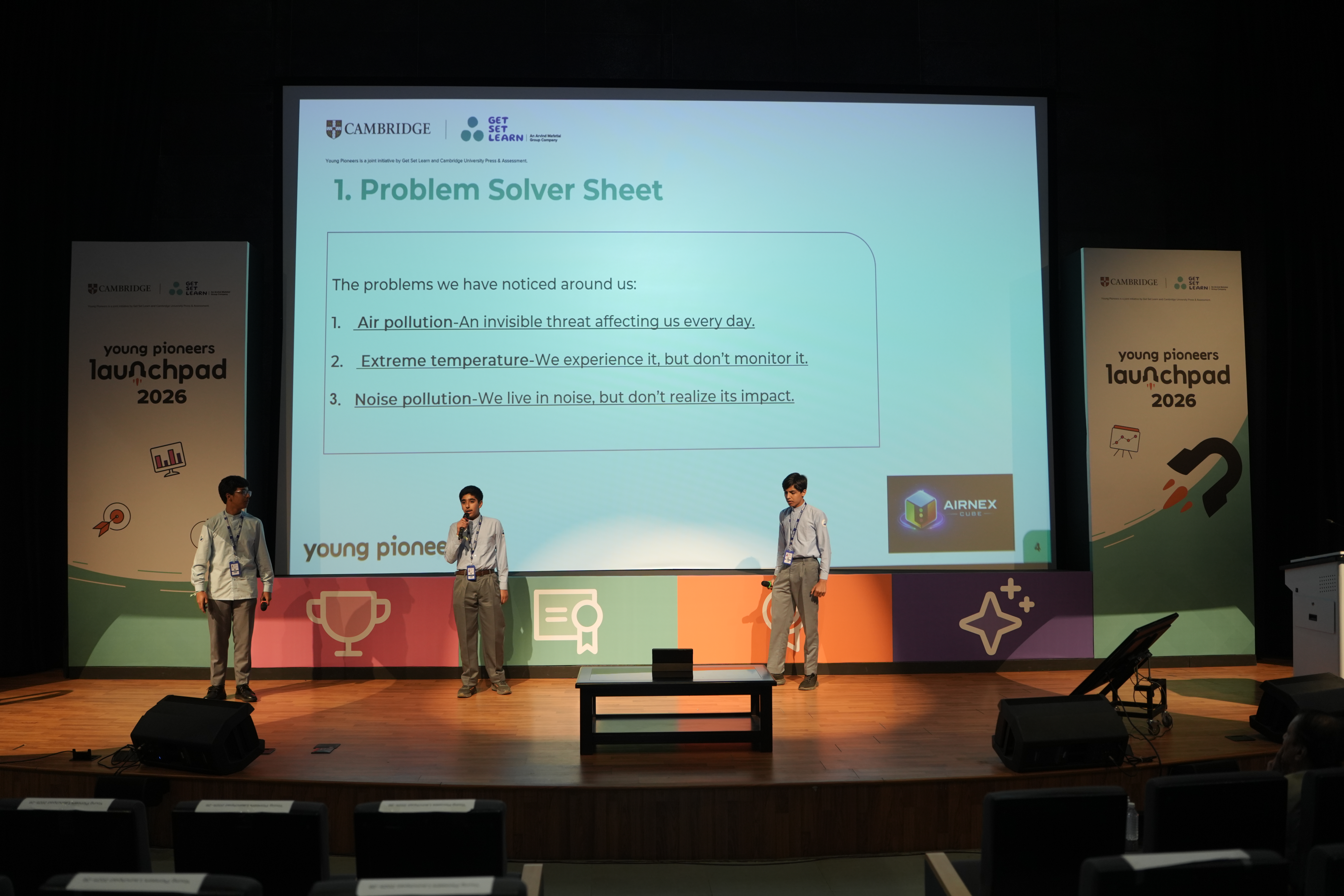 Three students on stage presenting the problems they set out to solve